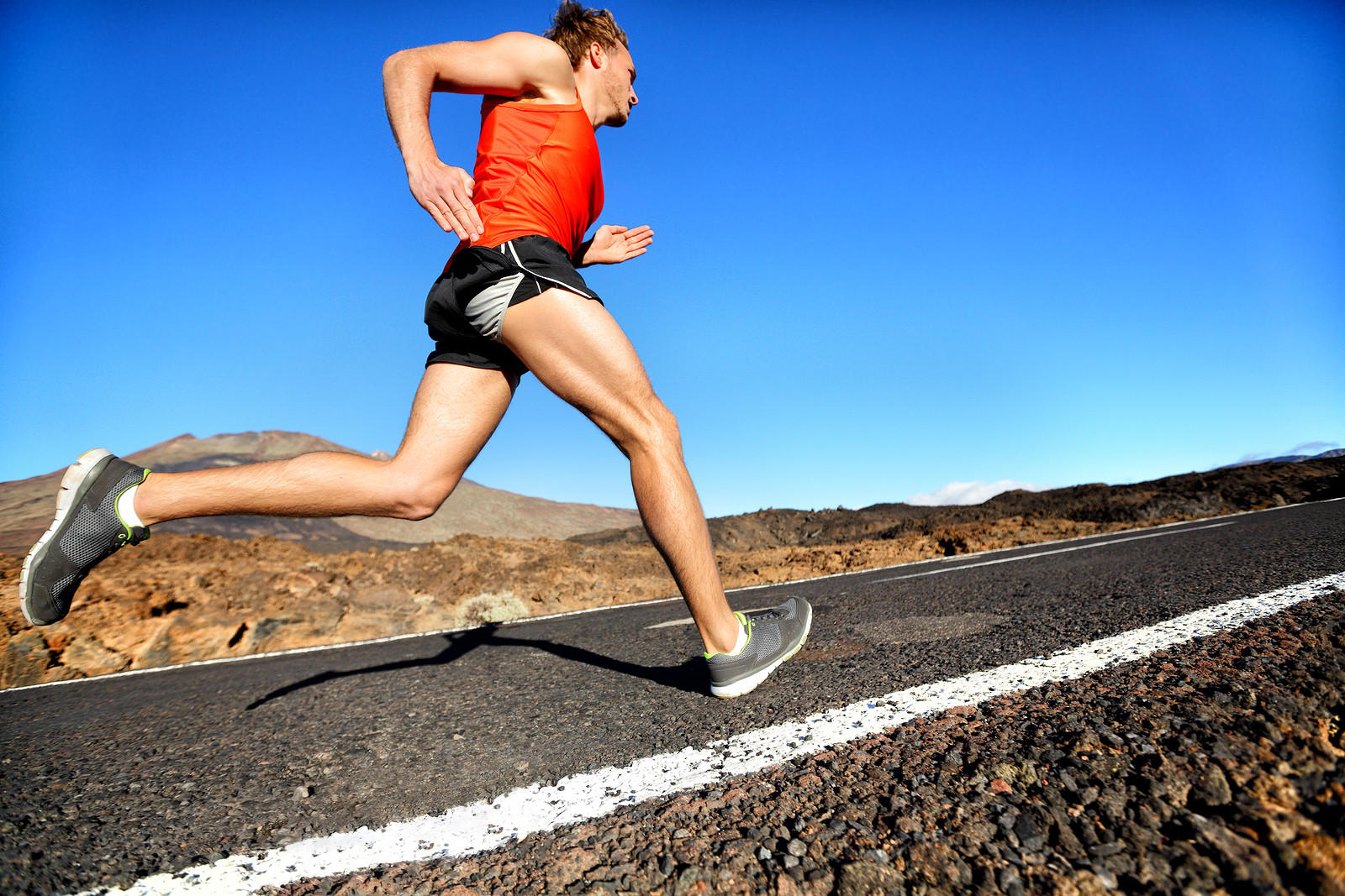 Runner man running sprinting for success on run. Male athlete runner training at fast speed. Muscular fit sport model sprinter exercising sprint on mountain road. Full body length of Caucasian model.